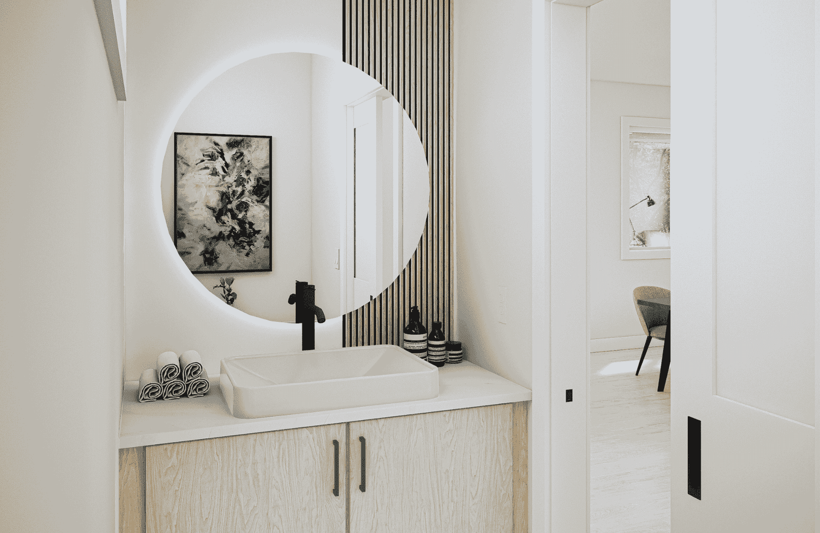 Modern bathroom with a circular backlit mirror, rectangular sink, and light wood vanity with black handles.